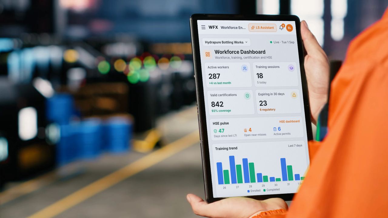Engineer in a production hall holding a tablet with the WFX Workforce Dashboard